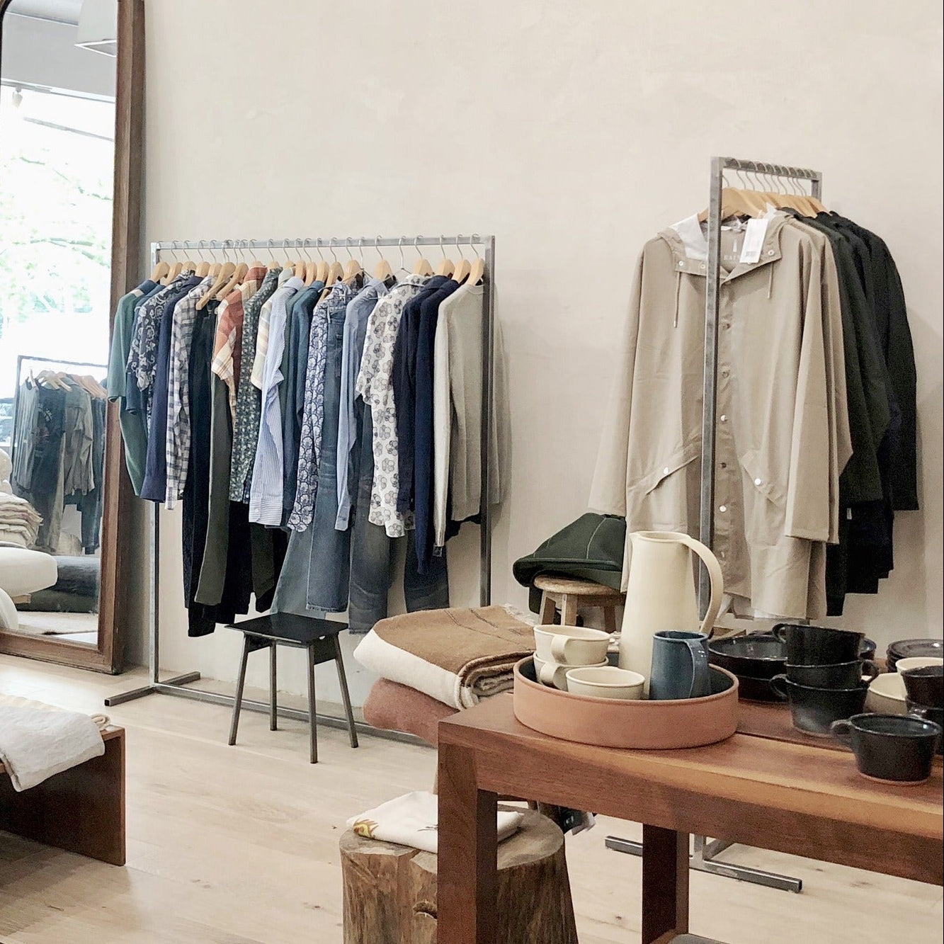 Clothing store interior with racks of clothes and a table with items on it.