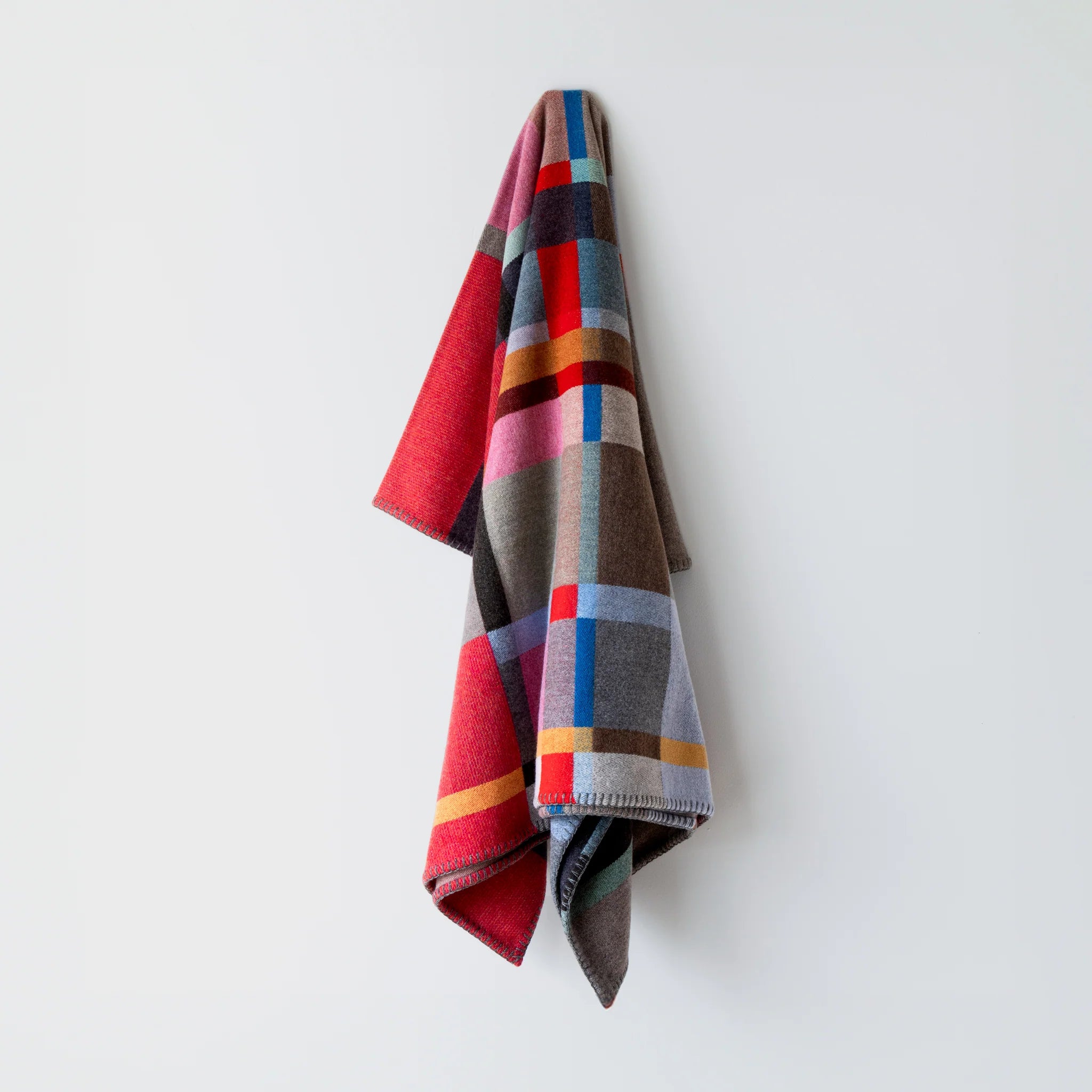 Colorful wool block plaid blanket by Wallace Sewell Lasdun draped over a white wall