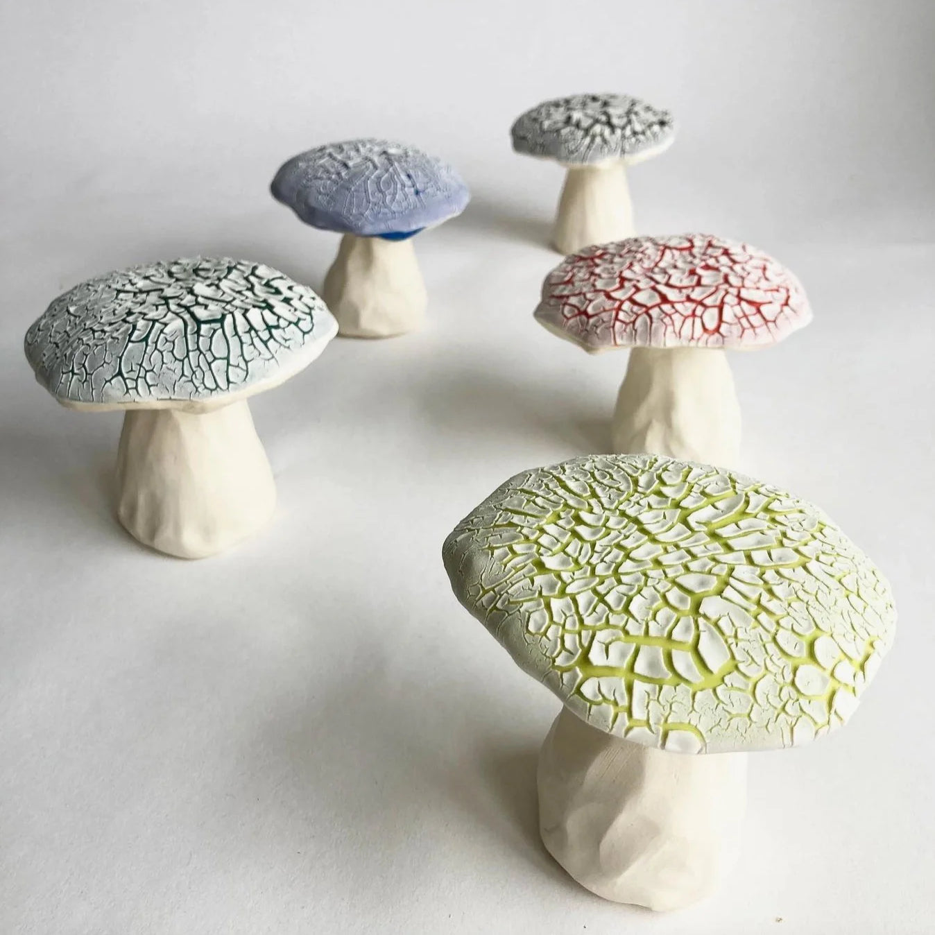 Set of ceramic mushrooms with textured caps on a white background