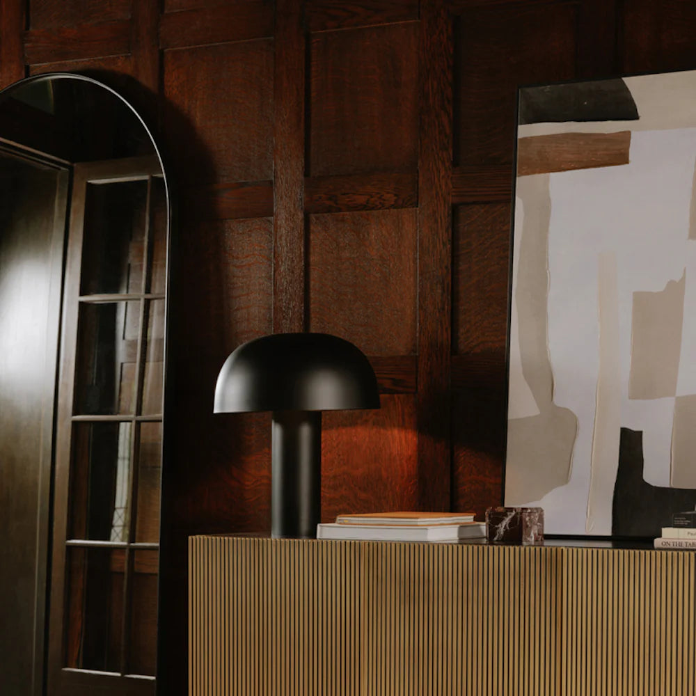 Black table lamp on a wooden surface with abstract art in the background for luxury interiors